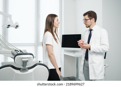 Happy Male Dentist Standing Near Dental Unit With Caucasian Female Patient With A Smile. Visit To Dentist Concept