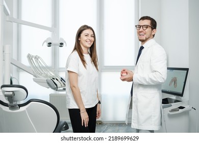 Happy Male Dentist Standing Near Dental Unit With Caucasian Female Patient With A Smile. Visit To Dentist Concept