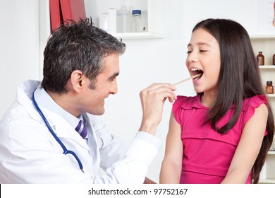 Happy Male Doctor Examining Child Mouth In Clinic.