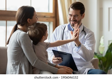 Happy male doctor have fun cheer support small 7s boy patient at visit to clinic with mom. Caring pediatrician give high five make deal with little child in hospital. Children healthcare concept.