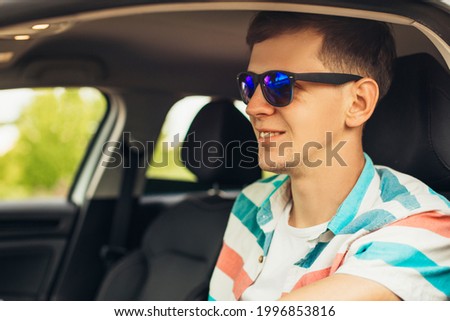 Happy male driver smiling, young man driving his car while sitting in car with open front window