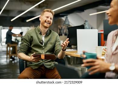 Happy Male Entrepreneur Using Digital Tablet And Having Fun While Talking To Female Colleague At Work.