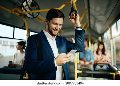 Happy Male Entrepreneur Using Mobile Phone And Text Messaging While Commuting By Public Bus.