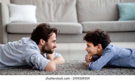 Happy Male Family. Profile Portrait Of Father And His Son Lying On Carpet, Looking At Each Other And Smiling, Spending Time Together At Home, Side View, Panorama