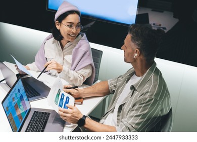 Happy male and female partners with digital laptops communicate about business trade during brainstorming in office, successful graphic designers analyzing report documents and marketing - Powered by Shutterstock