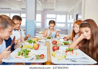 Happy male and female students eating food while sitting together in school cafe - Powered by Shutterstock