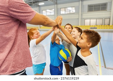 Happy male and female students giving high five to coach during gym class - Powered by Shutterstock
