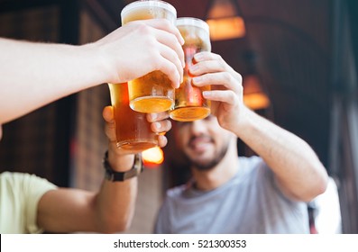 Happy male friends clinking with beer mugs in pub