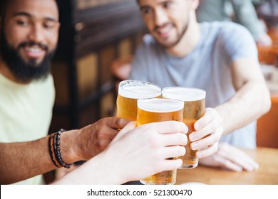 Happy Male Friends Clinking With Beer Mugs In Pub