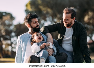 Happy Male Gay Family In The Park With Their Little Daughter