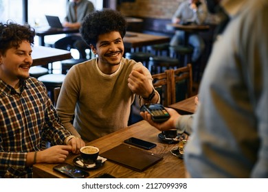 Happy Male Guest Using Smart Watch While Making Contactless Payment In A Cafe.