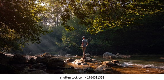 Happy male hiker trekking outdoors in forest near river. idea and concept of adventure, discovery and travel - Powered by Shutterstock