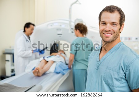 Happy male nurse with colleague and doctor preparing patient for CT scan in hospital