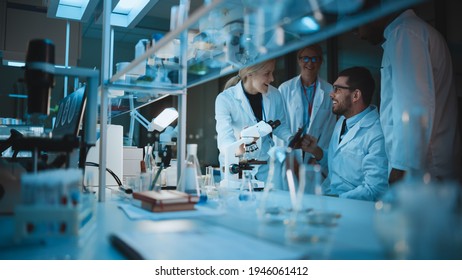 Happy Male Reseach Scientist Makes an Important Discovery While Researching Samples Under the Microscope. Happy Colleagues Congratulate it and Share Success with Fellow Bioengineers. - Shutterstock ID 1946061412
