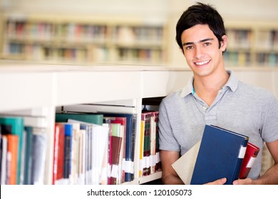 Happy male student holding books at the library