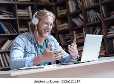 Happy male student online teacher wear headphone talk video calling looking at laptop computer screen do conference chat communicate with skype tutor, distance education e learning course in library