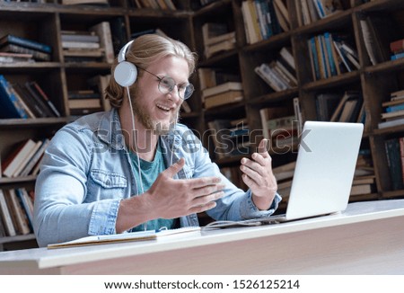 Happy male student online teacher wear headphone talk video calling looking at laptop computer screen do conference chat communicate with skype tutor, distance education e learning course in library