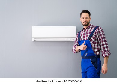 Happy Male Technician Gesturing Thumb Up Near Air Conditioner