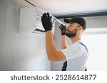 Happy Male Technician Repairing Air Conditioner.