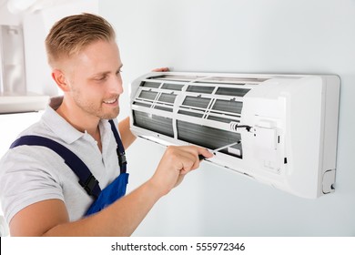 Happy Male Technician Repairing Air Conditioner With Screwdriver - Shutterstock ID 555972346