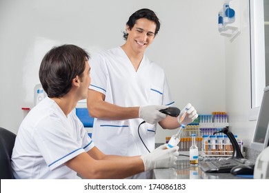 Happy male technicians scanning barcode on samples in laboratory - Powered by Shutterstock