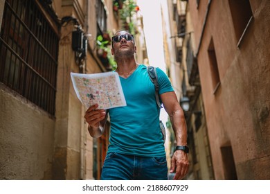 Happy Male Tourist Maps User Walking In Old Town Alley An Using A Map. Barcelona, Spain.