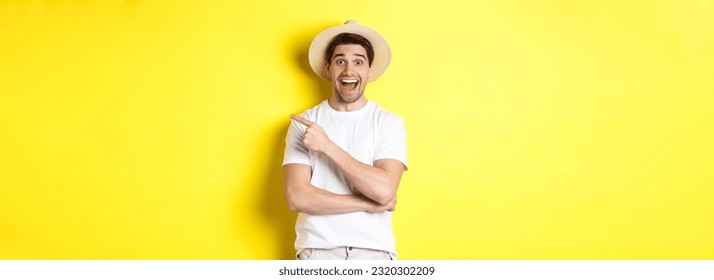 Happy male tourist in straw hat pointing finger right, showing promo offer on copy space, yellow background. Copy space - Powered by Shutterstock