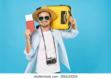 happy male tourist with yellow suitcase holding passport and visa tickets in hand