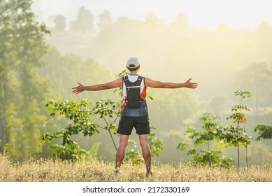 Happy Male Trail Runner Feeling Free And Running With Arms Raised In A Calm And Beautiful Place, Strong Trail Runner Exercising Standing In The Fresh Air In The Forest.