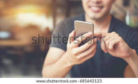 Happy male using smartphone at modern coffee shop, he chatting Online Messaging on mobile.
