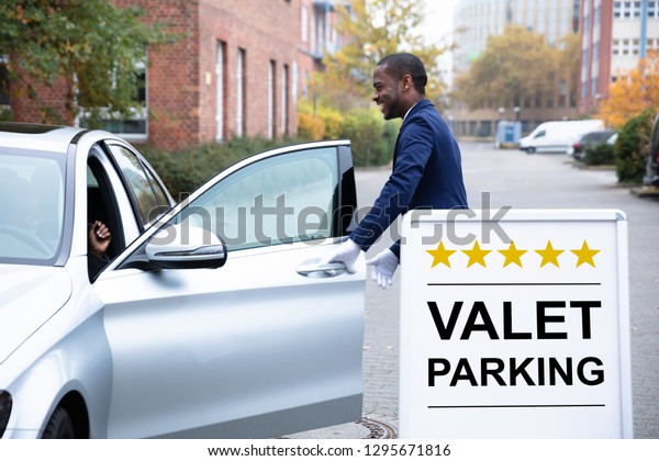 Happy\
Male Valet Opening Car Door Near Valet Parking\
Sign