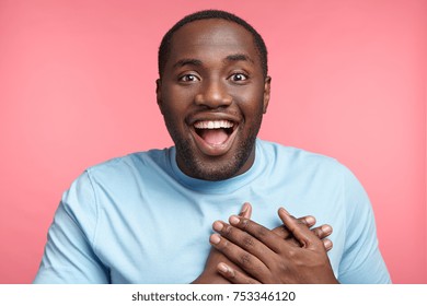 Happy male watches football match, rejoices victory of his favourite team, screams with excitement, has delightful expression. Friendly looking African male expresses positiveness