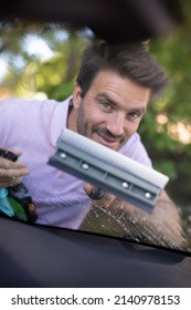 Happy Male Worker Cleaning Car Windshield