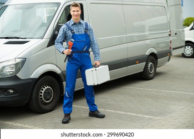 Happy Male Worker With Work Tool And Toolbox In Front Of Van