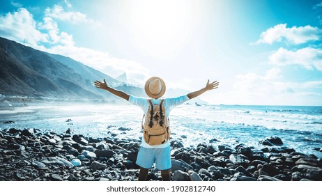 Happy man with arms up enjoying freedom on the beach - Hiker with backpack celebrating success outdoor - Blue filter - Powered by Shutterstock