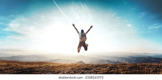 Happy man with arms up jumping on the top of the mountain - Successful hiker celebrating success on the cliff - Life style concept with young male climbing in the forest pathway  - Powered by Shutterstock