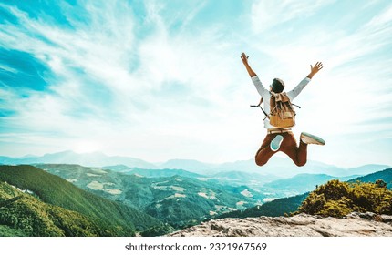 Happy man with backpack jumping on top of the mountain - Delightful hiker with arms up standing over the cliff - Sport and travel life style concept