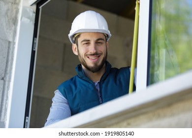 happy man builder infront of window with tape measure