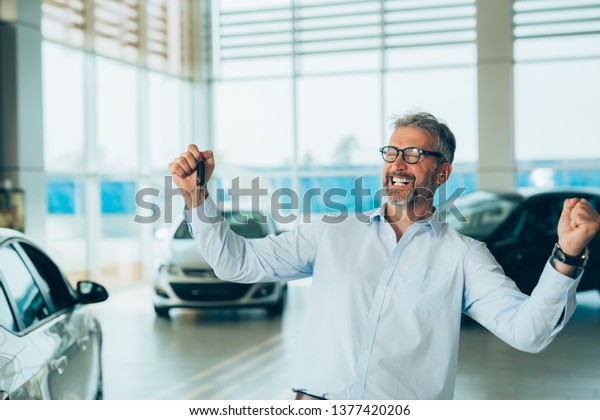 happy man in car\
showroom holding car keys