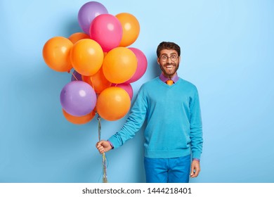 Happy Man Celebrates Anniversary Of Business Company, Comes On Corporate Party, Carries Colorful Air Balloons, Wears Glasses, Blue Neat Clothes Poses In Office. Cheerful Student Comes On Leaving Party