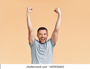 Happy man celebrating his success with winner gesture and hands up on beige background. victory, triumph and emotions concept      - Shutterstock ID 1493910653