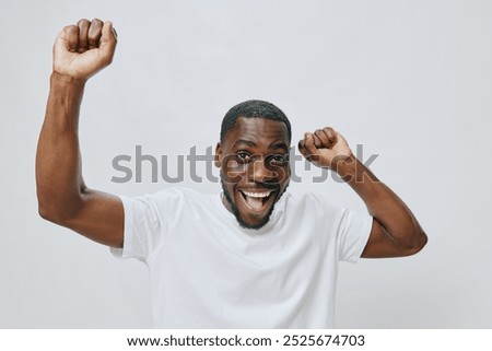 Similar – Cheerful man celebrating his success with a broad smile and raised fist in front of a neutral background