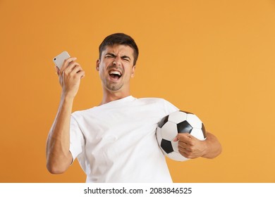 Happy man with cellphone and ball after winning of his sports bet on color background - Shutterstock ID 2083846525