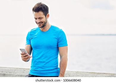 Happy man checking his phone during outdoors workout  - Powered by Shutterstock