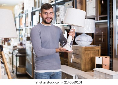 Happy Man Choosing Vintage Table Lamp In Shop Of Secondhand Furniture