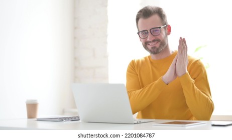 Happy Man Clapping While Using Laptop