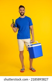 Happy man with cool box and bottle of beer on yellow background