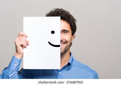 Happy man covering half his face with a smiling emoticon - Shutterstock ID 376687903