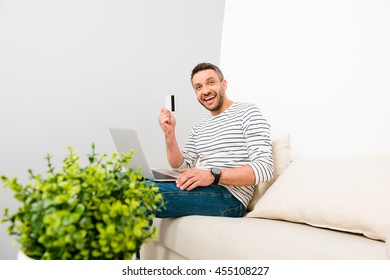 Happy man doing internet shopping and holding credit card