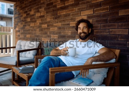 Happy man drinking coffee while relaxing on the porch. Copy space. 